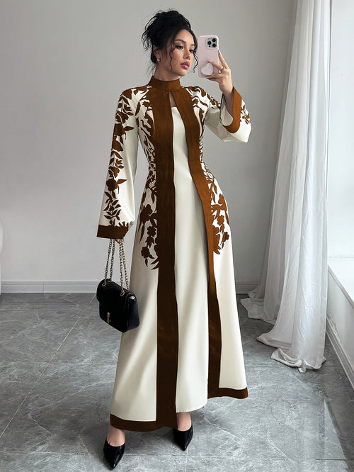 Woman taking a mirror selfie wearing a long, patterned dress in a room with light gray walls and a white curtain.