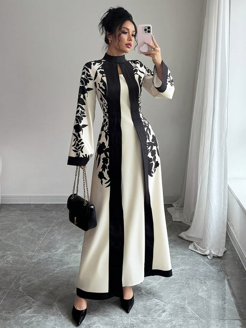Woman taking a mirror selfie wearing a black and white dress in a room with light gray walls and a white curtain.