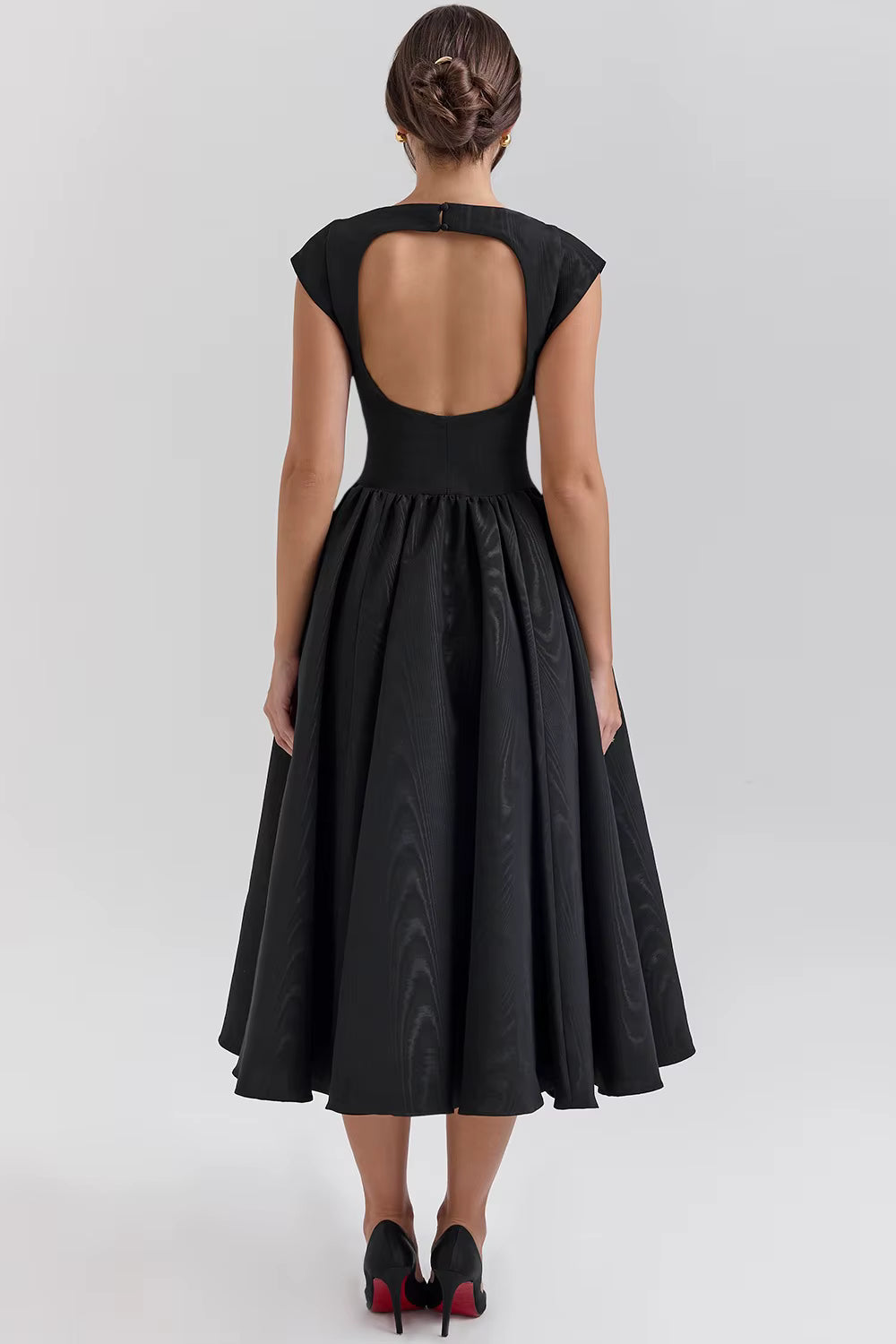 Black dress with open back worn by a model on a white background