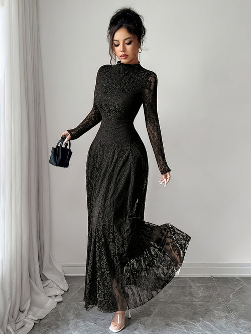 Woman wearing a long brown lace dress in a room with gray walls and a gray carpet.