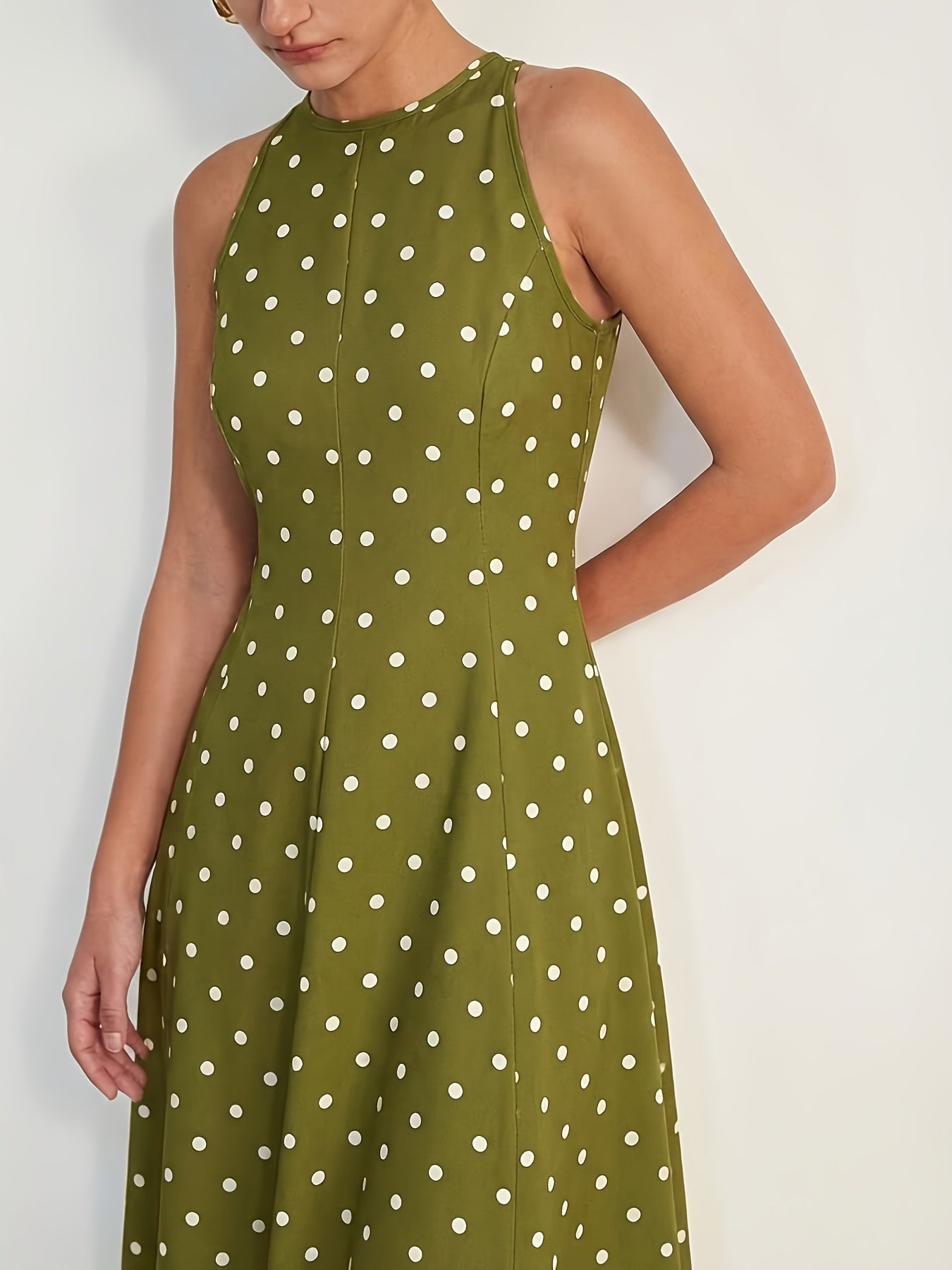 A sleeveless olive green dress with a white polka dot pattern, shown on a model against a plain light background.