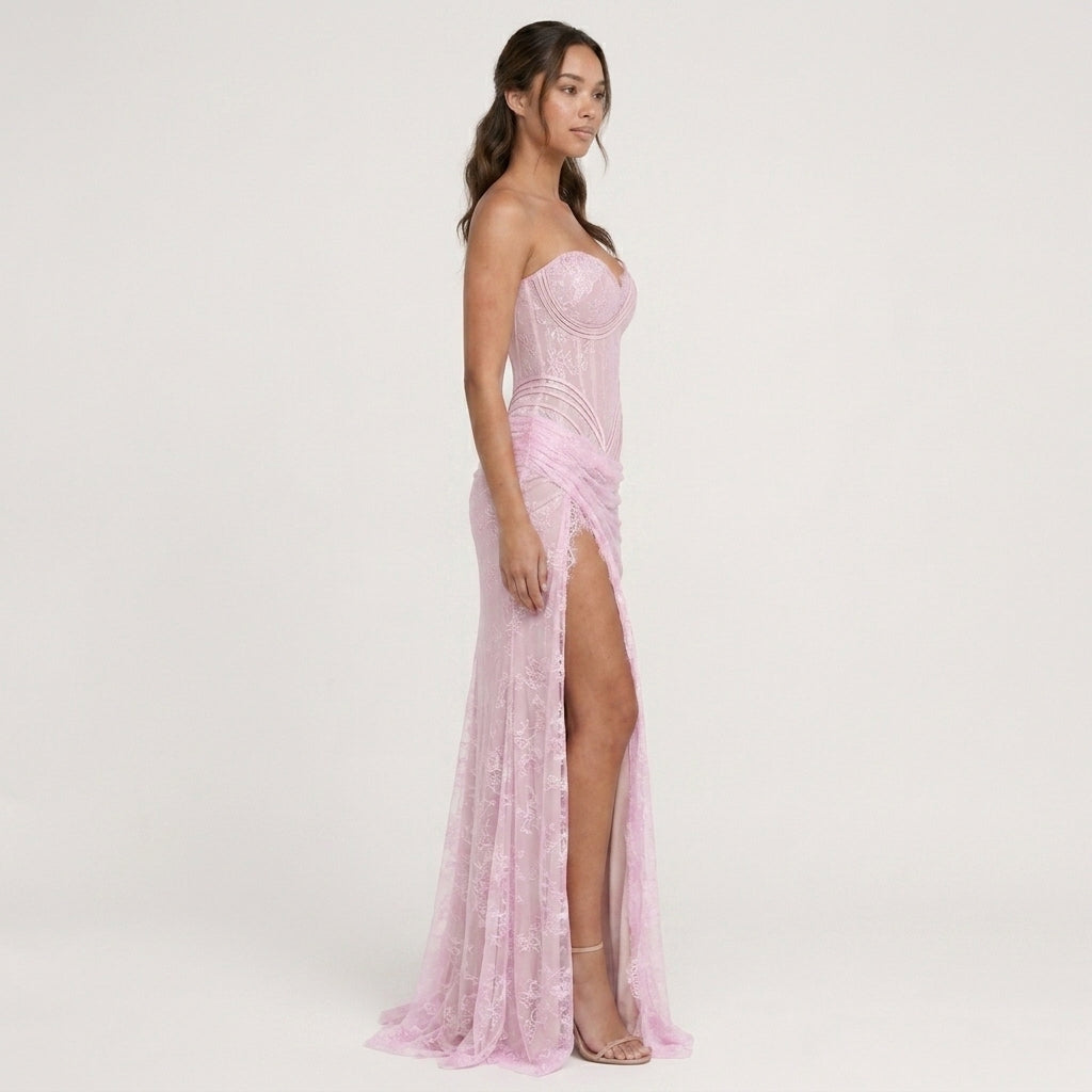 Woman wearing a pink strapless gown with a high slit on a white background
