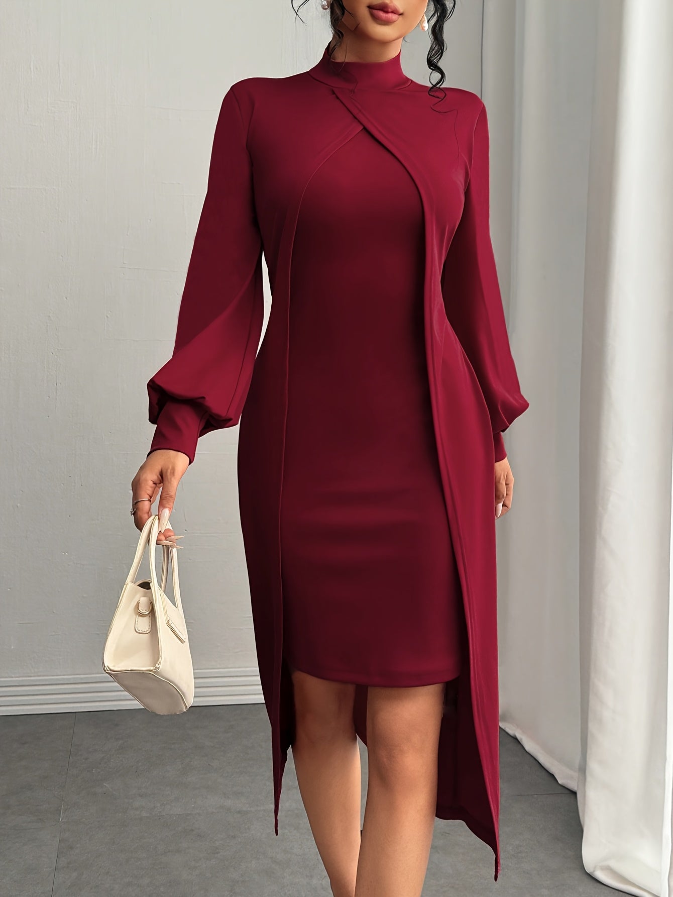 A woman wearing a long-sleeve high-neck bodycon dress in deep burgundy, styled with a matching long wrap cardigan, holding a small cream-colored handbag.
