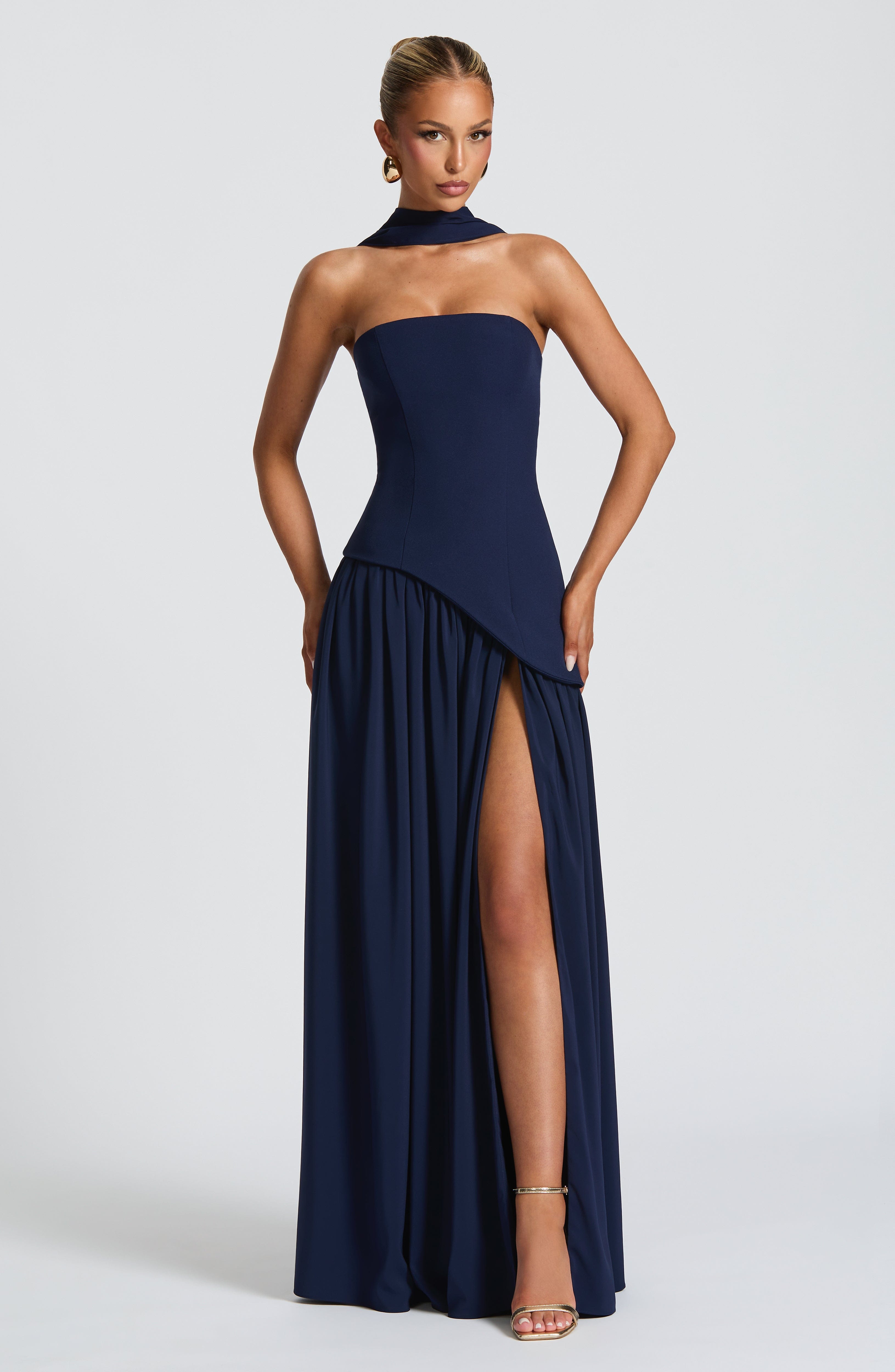 Navy blue strapless gown with a high slit on a white background
