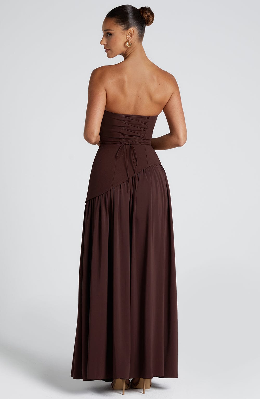 Woman wearing a brown strapless dress on a white background
