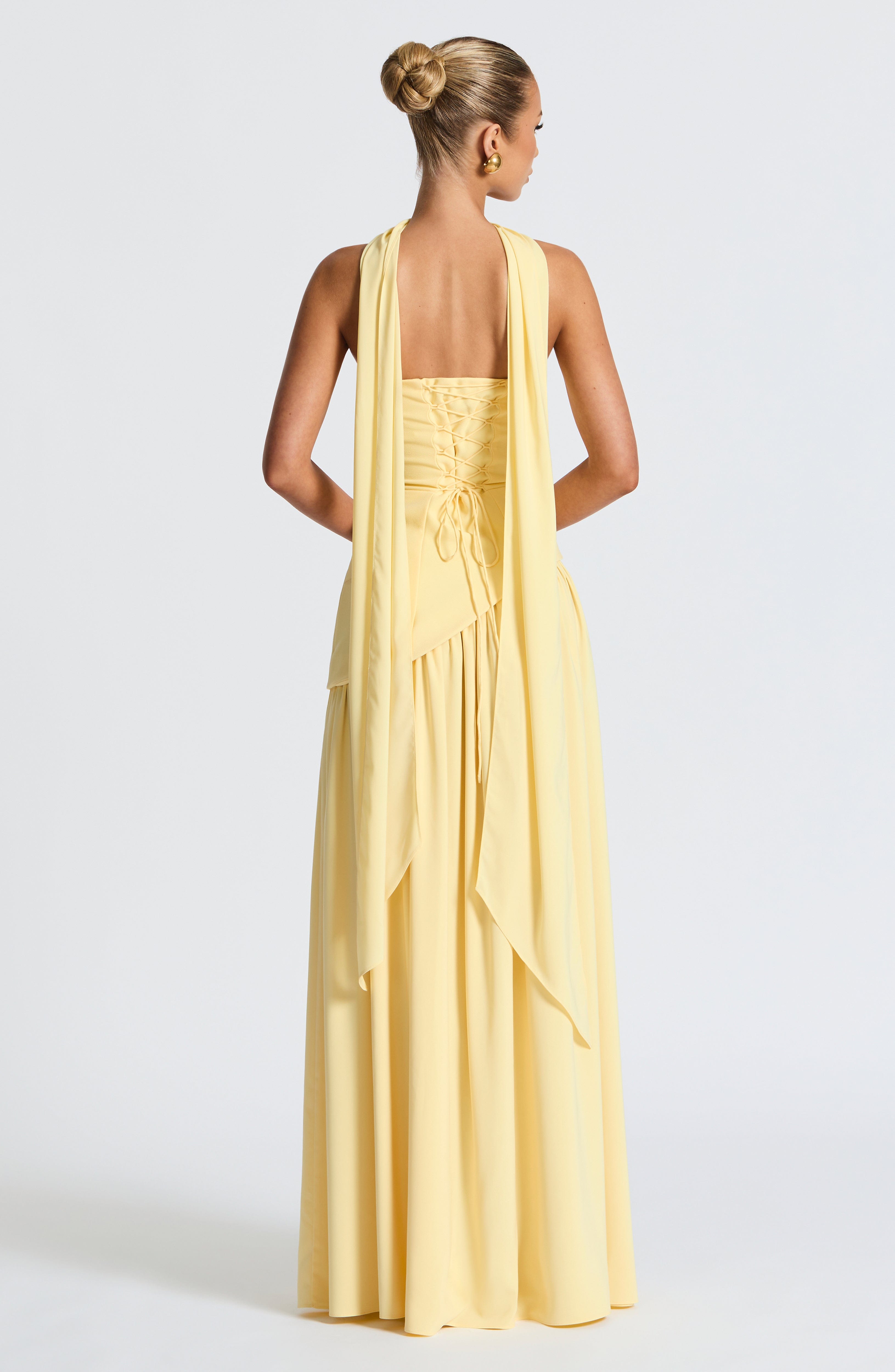 Woman wearing a yellow evening gown with a plain background