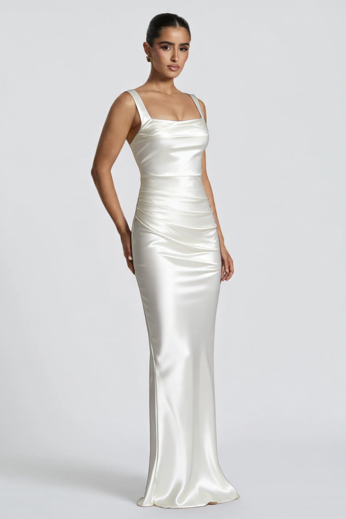 Woman wearing a white satin gown on a plain background