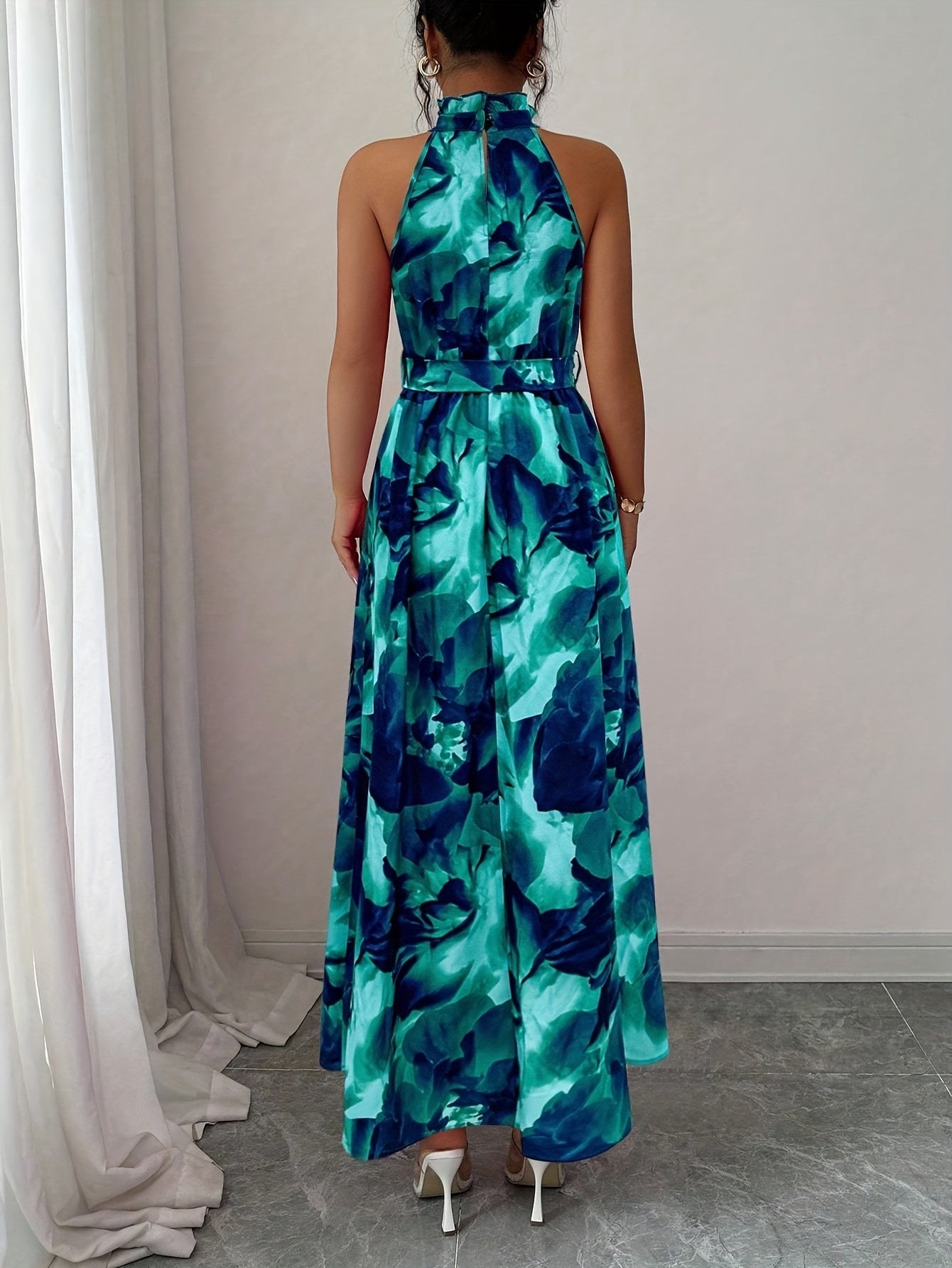 Woman wearing a blue and green floral dress against a neutral background